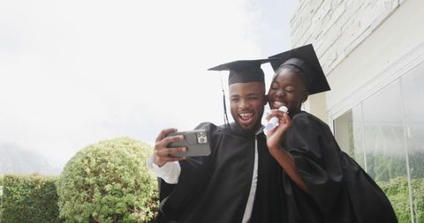 Joyful graduates smiling with diplomas in accomplishment celebration