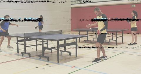 Recreational players playing table tennis in indoor gym with two tables and scanlines