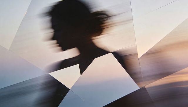 Blurring female silhouette streaking through fragmented glass shards with pastel gradient