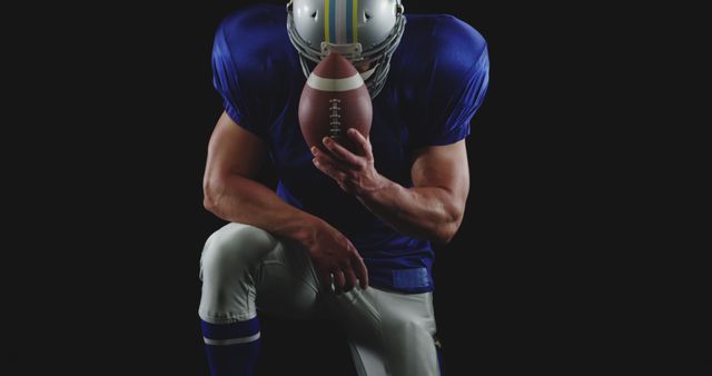 American Football Player Kneeling and Holding Ball Against Black Background - Download Free Stock Images Pikwizard.com