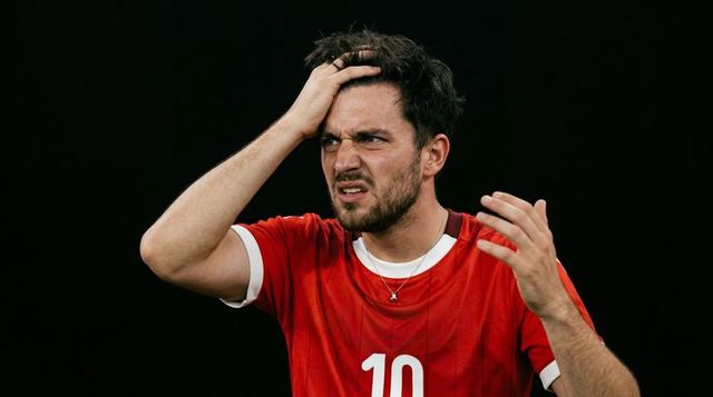 Soccer player holding head and showing frustration wearing red no 10 jersey, close-up