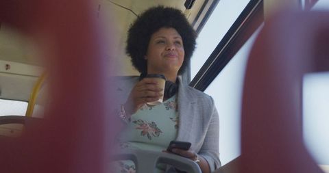 Happy biracial woman enjoying coffee commute on bus