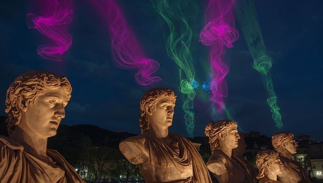 Neon ribbons illuminating classical marble statues on riverfront at night