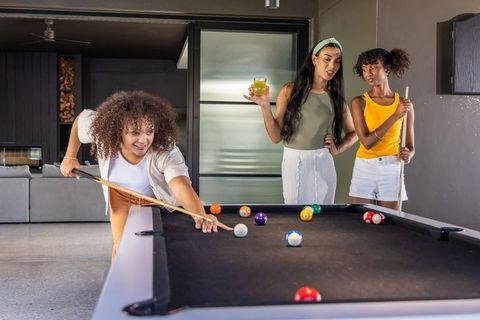 Multicultural women playing pool in modern game room, casual social leisure lifestyle