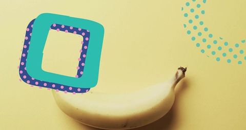 Ripe banana lying on yellow backdrop with turquoise pop-art shapes and polka dots