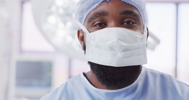 Image portrait of african american male surgeon wearing face mask in operating theatre, copy space. Hospital, medical and healthcare services.