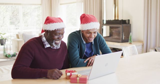 Happy african american father and adult son in christmas hats having laptop image call - Download Free Stock Photos Pikwizard.com