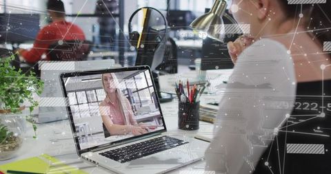 Woman Watching Video Call on Laptop at Modern Open-Plan Office Desk with Digital Overlay