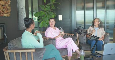 Recording podcast conversation with three women chatting in modern cozy lounge studio