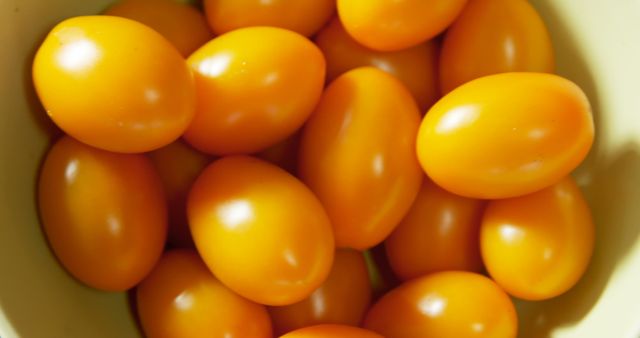 Close-up showing a bowl of fresh yellow cherry tomatoes with vibrant colors. Ideal for use in healthy eating campaigns, organic food advertisements, cooking blogs, nutrition articles, and gardening magazines.