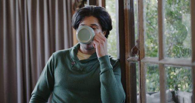 Man drinking morning coffee by window in cozy home - Download Free Stock Images Pikwizard.com