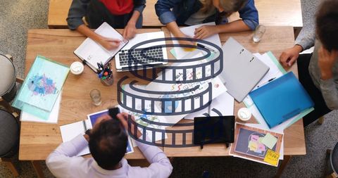 Diverse Team Brainstorming Around Wooden Desk with Documents and Laptop