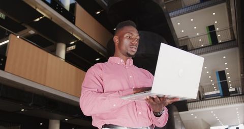 African American Professional Holding Laptop in Modern Office Atrium