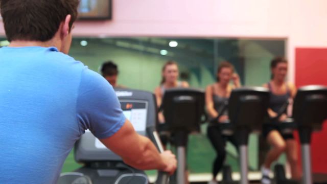 Trainer motivating a group of women during a spinning class at the gym. This video can be used for promoting health and fitness programs, gym memberships, and workout routines. Ideal for websites, brochures, or social media posts focused on fitness training and group exercise sessions.