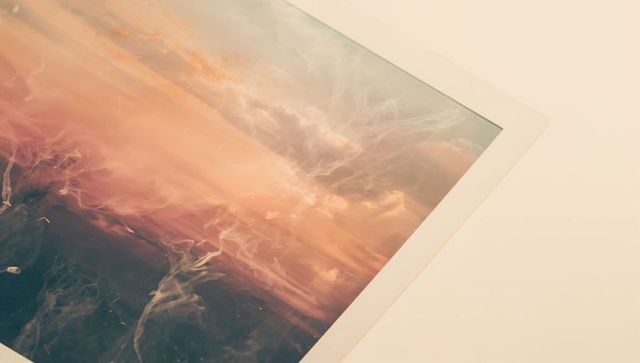 Printed art sheet leaning on beige tabletop showing marbled abstract gradient and veined texture