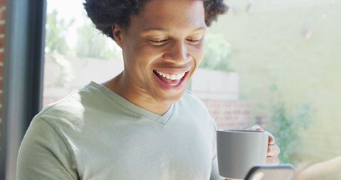 Man Enjoying Coffee and Using Smartphone at Home