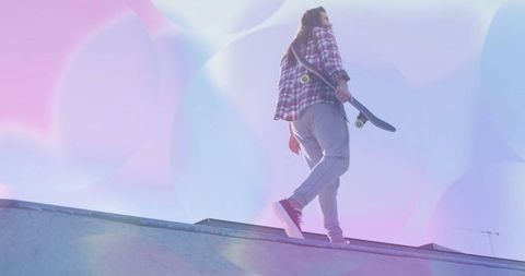 Teen carrying skateboard with dreamy light flares