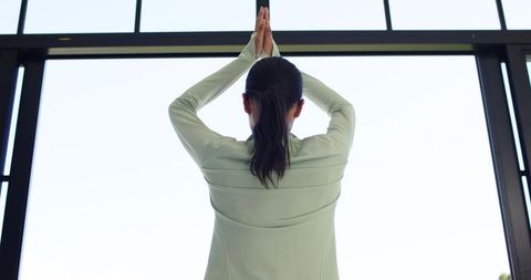 African woman practicing yoga in minimalist studio by floor-to-ceiling window morning light