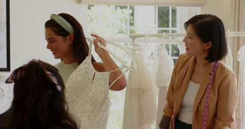 Bride selecting wedding dress with friends in bright bridal shop