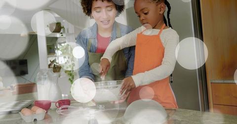 Young girl and caregiver baking together in bright kitchen, whisking batter