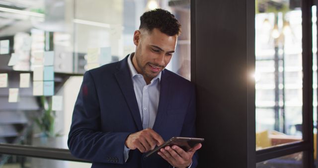 Confident Biracial Businessman Smiling While Using Tablet in Creative Office Space - Download Free Stock Images Pikwizard.com