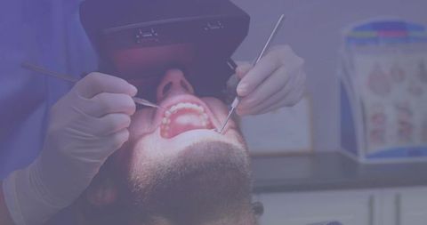 Male Patient Receiving Dental Examination Using Mouth Mirror and Explorer