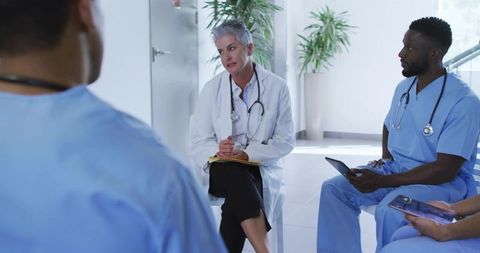 Senior physician leading multidisciplinary team discussion with nurses and residents in hospital