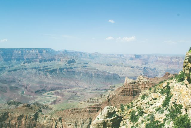 Stunning view of Grand Canyon with clear blue sky. Perfect for travel websites, nature blogs, educational materials on geology, and brochures for national parks. Captures the grandeur of natural rock formations and the expansive horizon.