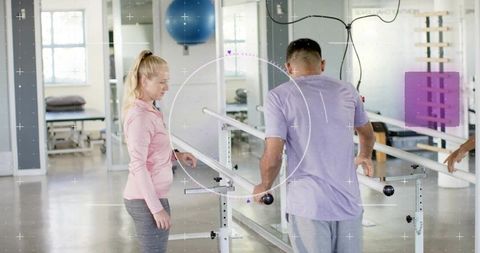 Physical therapist guiding patient during parallel-bar gait training in rehabilitation clinic