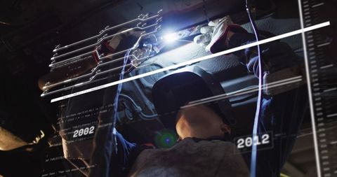 Female Technician Welding Under Car Chassis with Augmented Reality Schematics Overlay