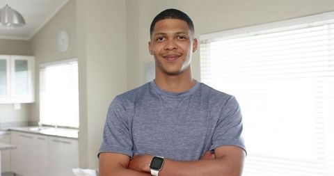 Confident african american man with arms crossed in modern sunlit kitchen
