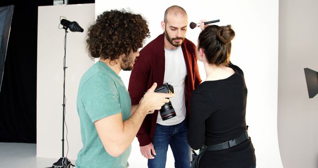 Focused diverse photographer and female make up artist preparing male model to photo session. Photography, model, lifestyle, work and professional, hobby.
