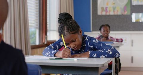 Focused Schoolgirls Writing in Classroom Setting