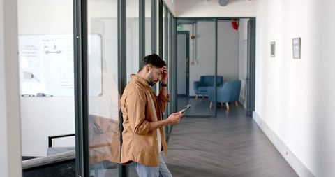 Businessman Checking Phone in Modern Office Hallway