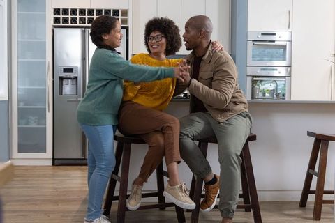 Multiracial family laughing and embracing at modern kitchen island with stools