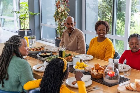 Diverse family gathering for warm home dinner with roasted chicken and sides