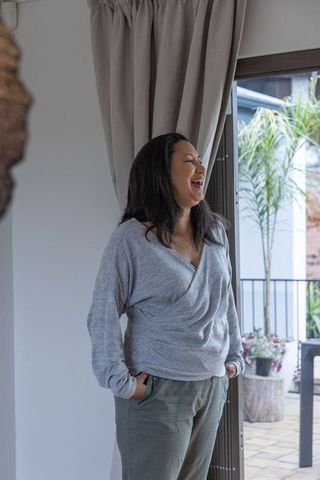 Woman relaxing with hands in pockets near sunny patio