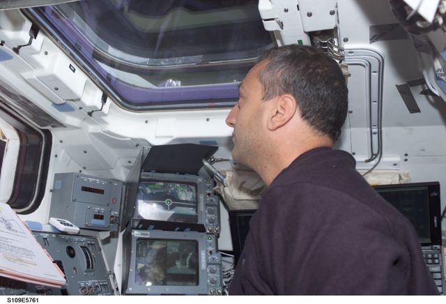 STS109-E-5761 (9 March 2002) --- Astronaut Michael J. Massimino, STS-109 mission specialist, looks through an overhead window on the aft flight deck of the Space Shuttle Columbia during the crew&#0146;s final interface with the Hubble Space Telescope (HST). The telescope was released at 4:04 a.m. (CST).  The image was recorded with a digital still camera.