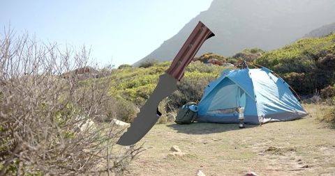 Floating tactical survival knife over campsite with blue tent in mountain wilderness