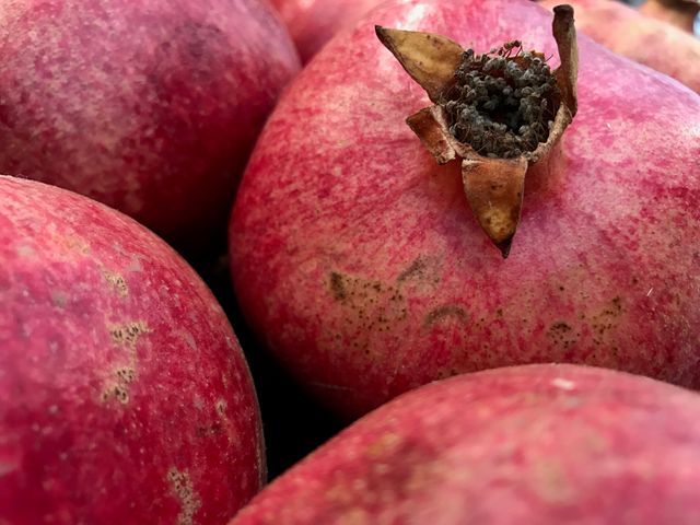 Close-up view of vibrant red pomegranates with rich texture. Perfect for adding visual appeal to marketing materials related to healthy eating, cooking, or organic produce. Ideal for promoting juicing products, wellness programs, or highlighting superfoods in diet-related photography.