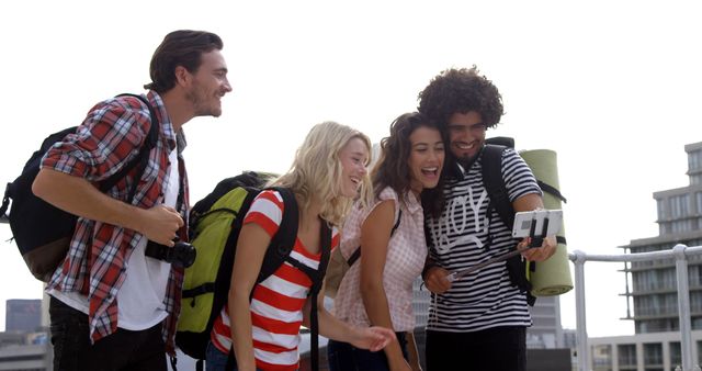 Group of young friends standing on rooftop, taking a selfie with smartphone. Bright, cheerful expressions show excitement and camaraderie during their urban adventure. Perfect for marketing materials related to travel, adventure, friendship, and youthful experiences.