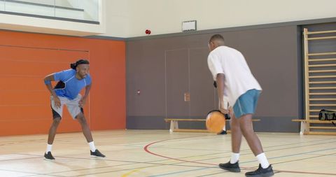 Basketball player dribbling past defender during indoor training drill on gym hardwood