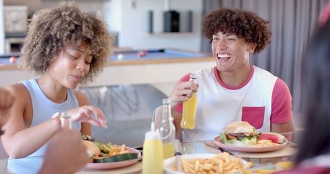 Diverse Friends Relishing Burgers and Drinks at Dining Table