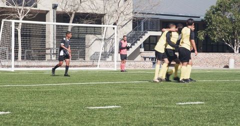 Youth soccer team celebrating goal on sunny day