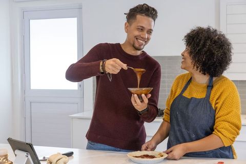 Couple baking homemade pie together in bright modern kitchen, sharing smiles