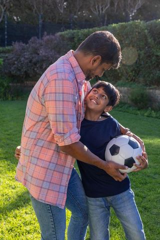 Father and Son Bonding with Soccer Outdoors in Backyard