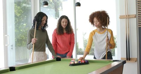 Friends Playing Pool in Sunlit Game Room Racking Billiard Balls and Sharing Laughter