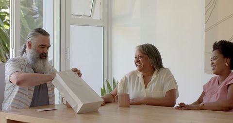 Happy Family Gathering as Gift is Exchanged Around Table