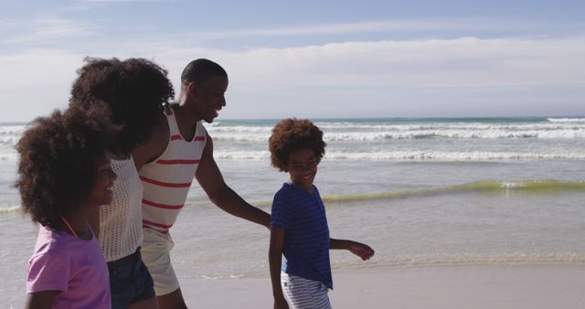 A joyful family is walking together on a beautiful beach. The adults, accompanied by children, are enjoying their time by the ocean, reflecting family bonding and leisure. This can be used for promoting family holidays, travel brochures, summer vacation themes, or lifestyle blogs encouraging quality family time at the beach.