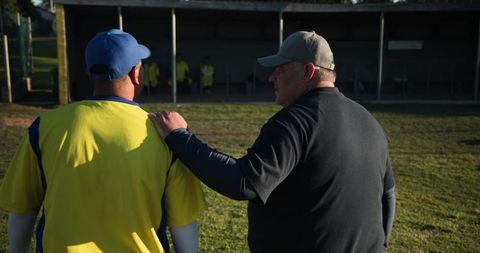 Baseball coach guiding player off field showing mentorship team leadership and support
